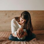 A heartwarming scene of a mother gently holding her baby on a bed, captured in a cozy bedroom setting.