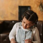 Child focusing on handmade crafts using colorful clay at a wooden table indoors.
