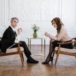 Two women engaged in an intense conversation in a modern office setting.