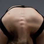 Close-up of a woman in a yoga pose highlighting the spine and back muscles.