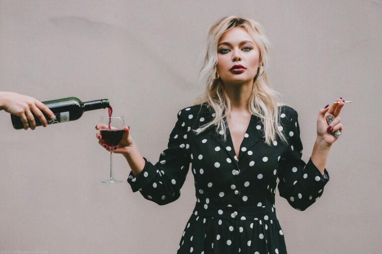 Chic woman enjoying wine and smoking, showcasing modern lifestyle and elegance.
