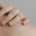 A gentle close-up of a hand resting on a person's shoulder, emphasizing skin texture.