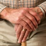 A detailed image of elderly hands clasping a wooden cane, symbolizing aging and support.