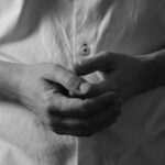 grayscale photo of persons hand on white textile