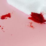 A white towel with red stains on a pink surface, depicting a messy spill.