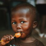 a young boy holding an orange in his mouth