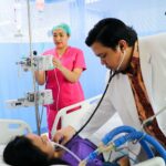a man laying in a hospital bed being examined by a nurse