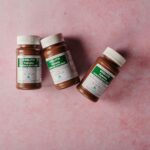 Three brown bottles of magnesium tablets on a soft pink background, ideal for health-themed content.