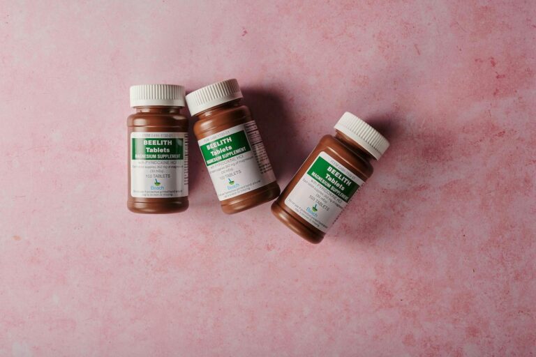 Three brown bottles of magnesium tablets on a soft pink background, ideal for health-themed content.
